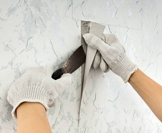 removing old wallpapers from wall with spatula during repair
